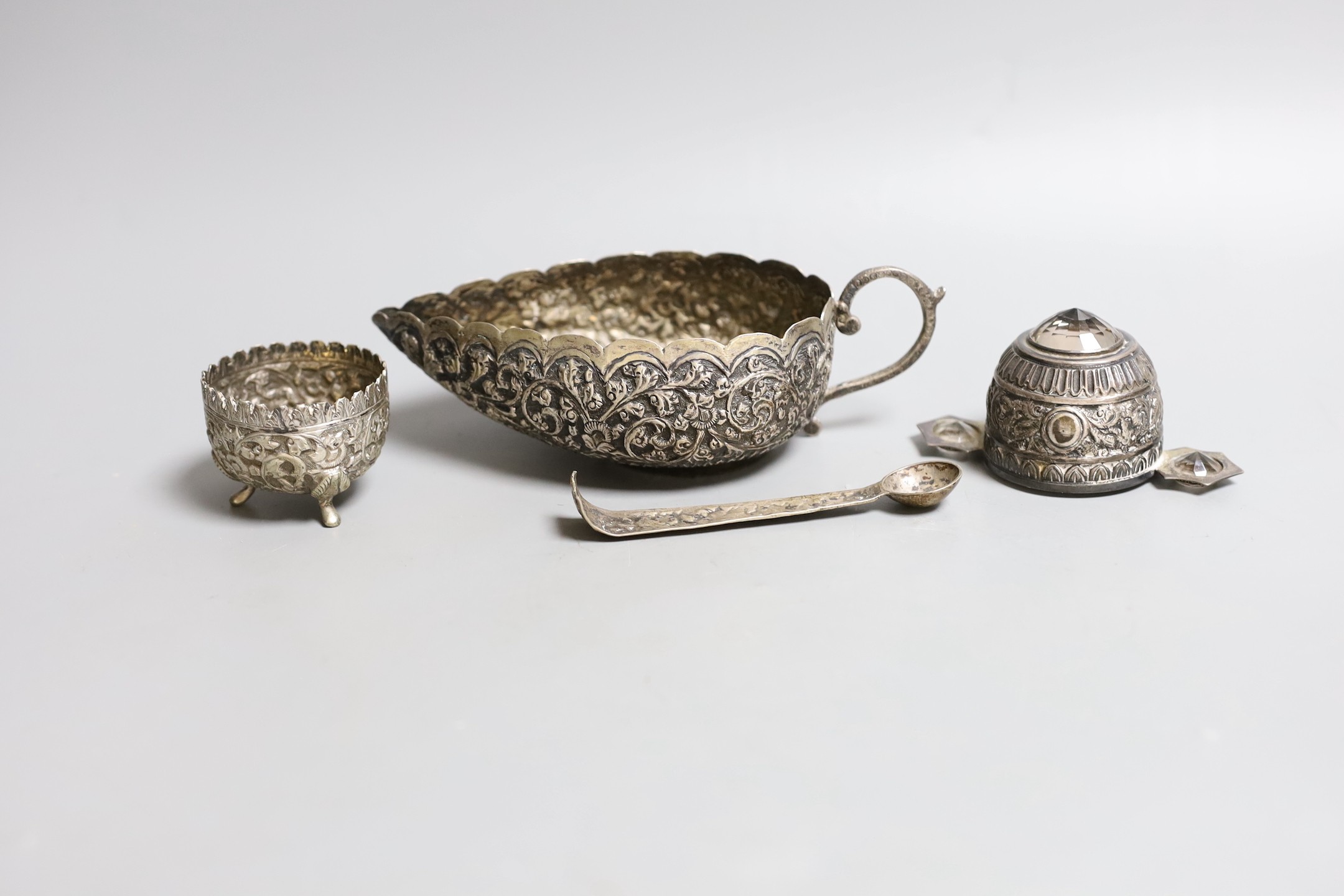 An Indian white metal gem set tasting cup, diameter 87mm, a sauce boat, salt and part of a pair of tongs (a.f.).